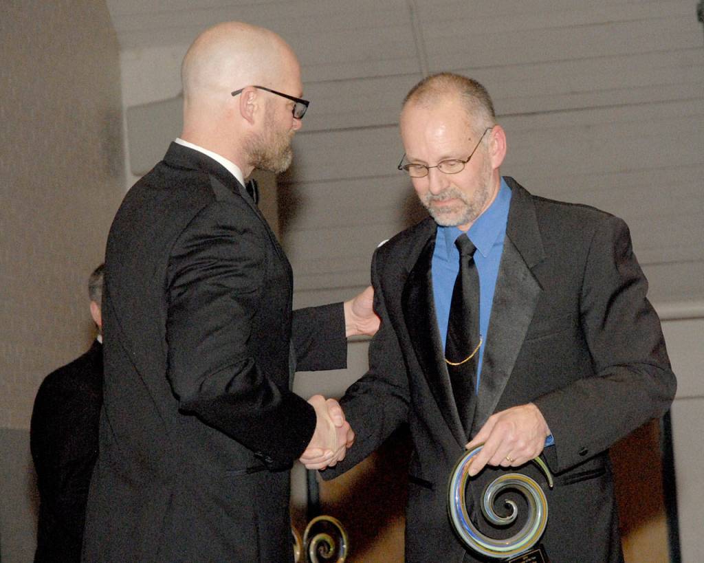 Community Award winner Doug Gailey, band director at Port Angeles High School, right, is congratulated by former Port Angeles School Board member Josh Jones after Gailey received the Educator of the Year award. (Keith Thorpe/Peninsula Daily News)
