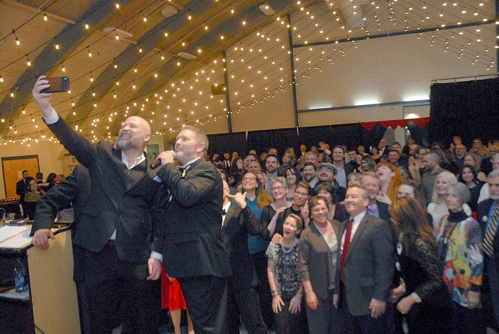 Community awards presenters Terry Ward and Tim Tucker take a selfie with the audience at the conclusion of the awards ceremony. (Keith Thorpe/Peninsula Daily News)
