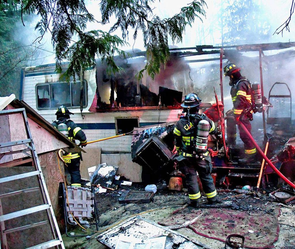 Clallam 2 Fire Rescue firefighters assess the damage on an RV that had been engulfed in flames on Old Deer Park Road in Port Angeles on Tuesday, Feb. 4, 2020. (Clallam 2 Fire Rescue)