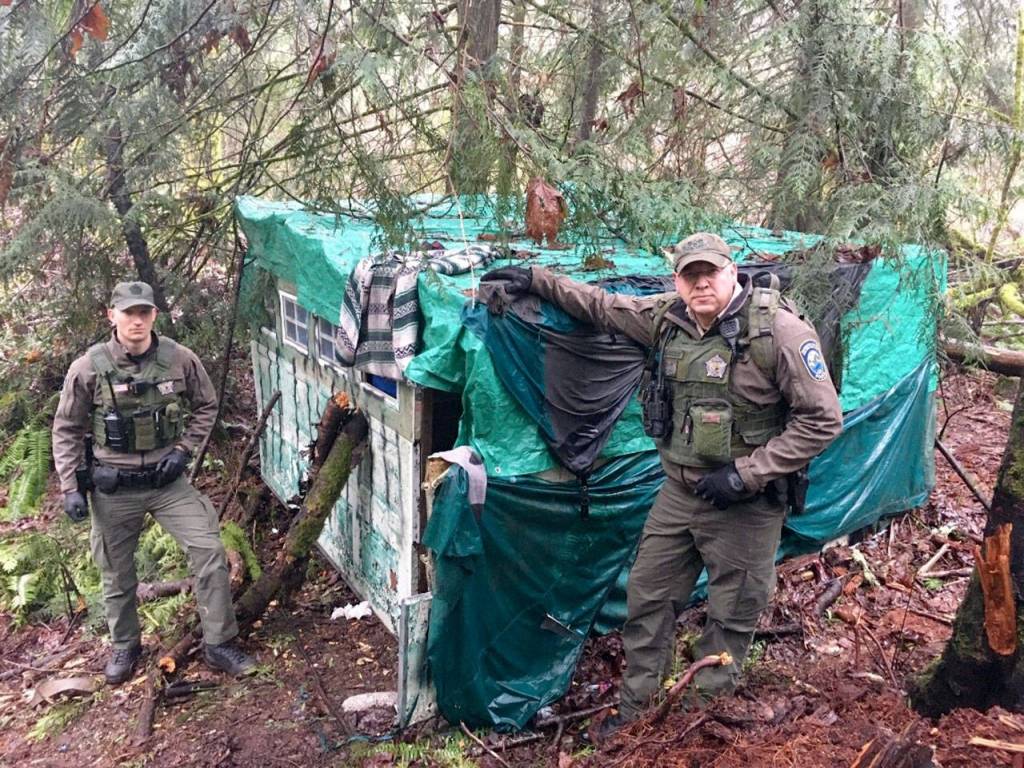 State Department of Fish and Wildlife officers Morgan Cooney and Bryan Davidson stand by a makeshift shelter at Morse Creek Unit east of Port Angeles. (Washington Department of Fish and Wildlife)