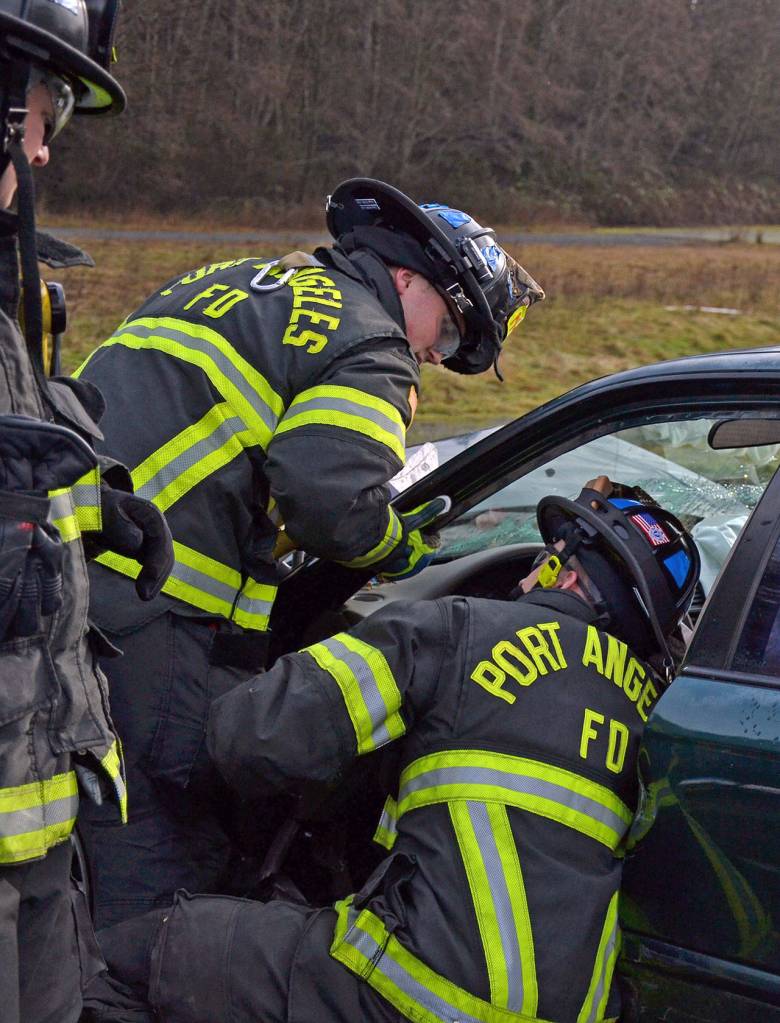 Port Angeles Fire Department paramedics/firefighters work on the best solution to extract a victim during a drill. (Laura A. Foster/Peninsula Daily News)
