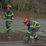 Capt. Kelly Ziegler, left, calls out orders as Lt. Jeremy Church rolls up a fire hose. (Laura A. Foster/Peninsula Daily News)