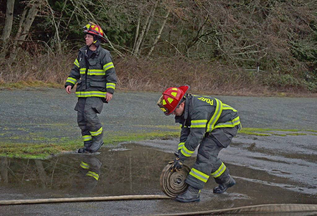 Capt. Kelly Ziegler, left, calls out orders as Lt. Jeremy Church rolls up a fire hose. (Laura A. Foster/Peninsula Daily News)