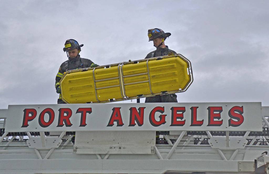 Paramedics Tyler Gage, left, and Doug Eaton secure a medical basket to the Port Angeles Fire Department fire truck. (Laura A. Foster/Peninsula Daily News)