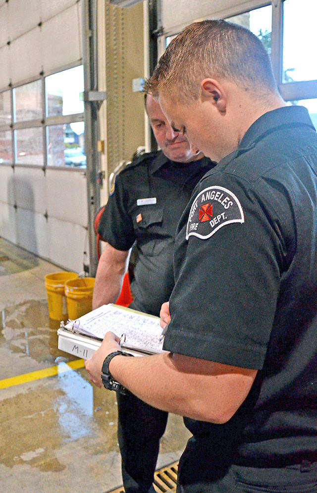Paramedic Tyler Gage, right, marks on a rig checklist as senior EMT Todd German verifies. (Laura A. Foster/Peninsula Daily News)