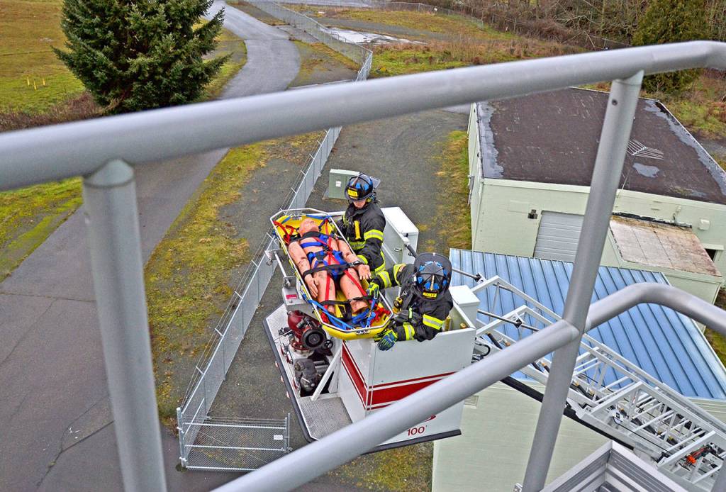 Paramedics Tyler Gage and Mike Ingraham descend to the ground after securing a patient during a ladder rescue drill. (Laura A. Foster/Peninsula Daily News)