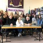 Sequim High School senior Gabrielle Happe, center in white, signs her letter of intent to play soccer at Edmonds Community College next year. Happe is joined by Sequim girls soccer head coach Derek Vandervelde, left center, Sequim athletic director Dave Ditlefsen, center right, and a number of her friends and soccer teammates. Happe will be joined at Edmonds by Port Angeles soccer player Lucah Folden.