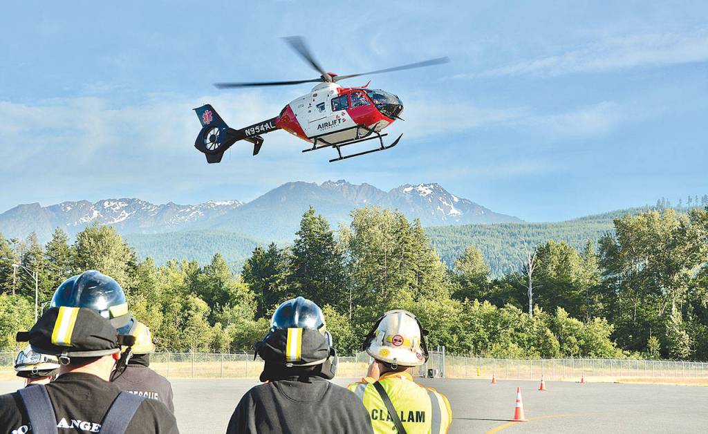 An Airlift Northwest helicopter lands in front of a group of Clallam firefighters recently. Airlift Northwest will no longer be reciprocating care for other air medical company memberships, such as Life Flight Network, starting March 25. (Jay Cline)