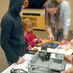 North Olympic Library System information technology specialist Bob Allen assists Lincoln Anton, 11, and Sydney Anton, 9, with computer disassembly. (Keith Thorpe/Peninsula Daily News)