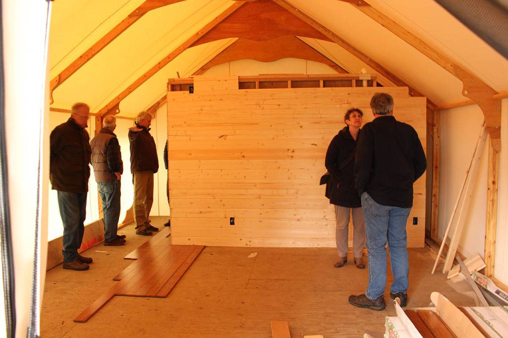 Members of the Friends of Fort Worden, the Fort Worden Public Development Authority and the Fort Worden Coordinating Committee tour one of the glamping tents that is still under construction. (Zach Jablonski/Peninsula Daily News)