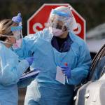 Theresa Malijan, a registered nurse, right, talks with medical assistant Miriam Fuentes as Malijan prepares to take a nasopharyngeal swab from a patient at a drive-through COVID-19 testing station for University of Washington Medicine patients Tuesday, March 17, 2020, in Seattle. The appointment-only drive-through clinic began a day earlier. Washington leads the country in the number of deaths, with most being associated with a nursing home in Kirkland. By Monday, the number of positive cases topped 900. (Elaine Thompson/The Associated Press)