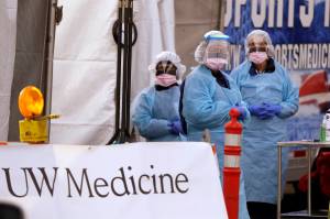 Medical personnel wait for a driver to pull up at a drive-through COVID-19 testing station for University of Washington Medicine patients Tuesday, March 17, 2020, in Seattle. The appointment-only drive-through clinic began a day earlier. Health authorities in Washington reported more COVID-19 deaths in the state that has been hardest hit by the outbreak. (Elaine Thompson/The Associated Press)