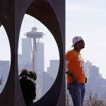 Issa Barry looks out over the Seattle skyline, including the iconic Space Needle, as he stands near a sculpture at a popular park Friday. People in the state are being asked to maintain physical distance from others to help stop the spread of COVID-19. (AP Photo/Elaine Thompson)