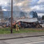 Firefighters work to extinguish a residential fire on Center Road near the intersection of Center Road and East Columbia Street. (Zach Jablonski/Peninsula Daily News)