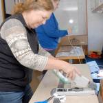 Volunteers Donna Fraser of Port Angeles, front, and Lori Shafer of Joyce fashion homemade face shields to be used by first responders when interacting with potential COVID-19 patients. The pair were working Wednesday in the countys emergency management vehicle outside the Clallam County Courthouse in Port Angeles. (Keith Thorpe/Peninsula Daily News)