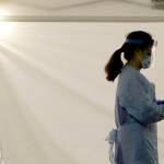 A nurse at a drive-up coronavirus testing station set up by the University of Washington Medical Center wears a face shield and other protective gear in this March 13 file photo as she waits by a tent in Seattle. Experts and health officials who are trying to plan a response to the coronavirus outbreak are missing a critical piece of information – the number of health care workers who have tested positive for the disease. (Ted S. Warren/The Associated Press)