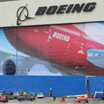 A worker walks near a mural of a Boeing 747-8 airplane at the companys manufacturing facility in Everett in this March 23 file photo. In an email to Washington employees on Sunday, the company said it is extending a planned two-week shutdown rather than reopening Wednesday due to coronavirus concerns. The decision affects about 30,000 of Boeings 70,000 employees in the state. Employees are receiving their regular salaries during the two-week shutdown but will have to transition to vacation or sick leave after that. (Ted S. Warren/The Associated Press)