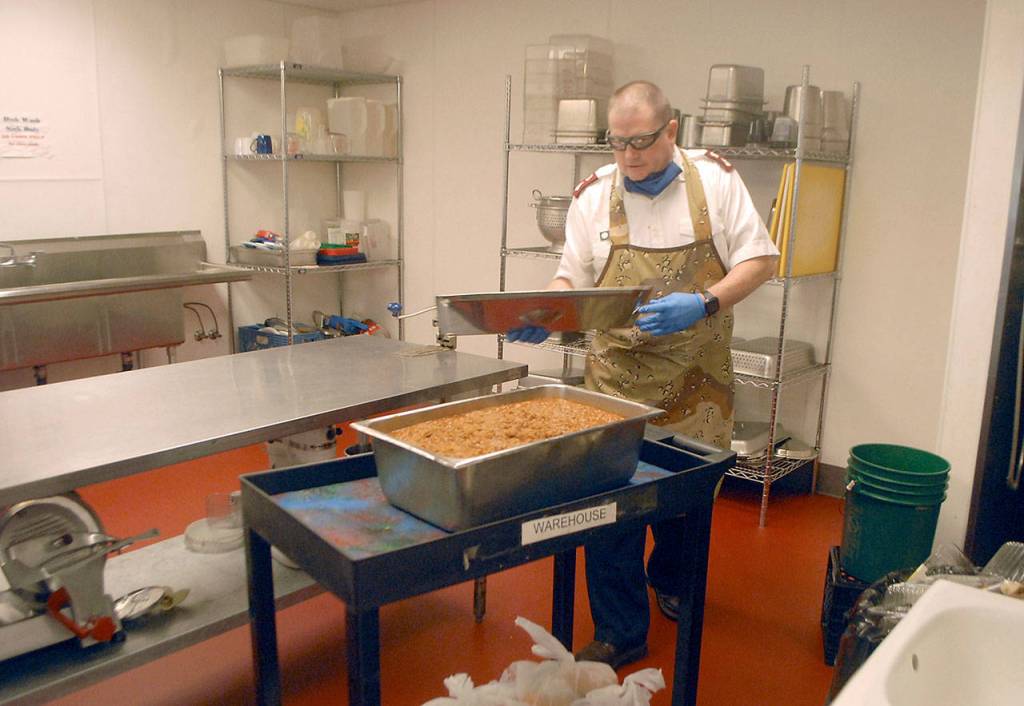 Salvation Army Major Ron Wehnau prepares to wheel a batch of pulled pork for sandwiches to the front of the organizations Port Angeles kitchen to make carry-out meals for the public on Friday. (Keith Thorpe/Peninsula Daily News)