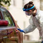 A medical worker asks a young man to roll down his window as Childrens National Hospital tests children and young adults for COVID-19 at a drive-through (drive-in) testing site at Trinity University on Thursday, April 16, 2020. (Andrew Harnik/The Associated Press)
