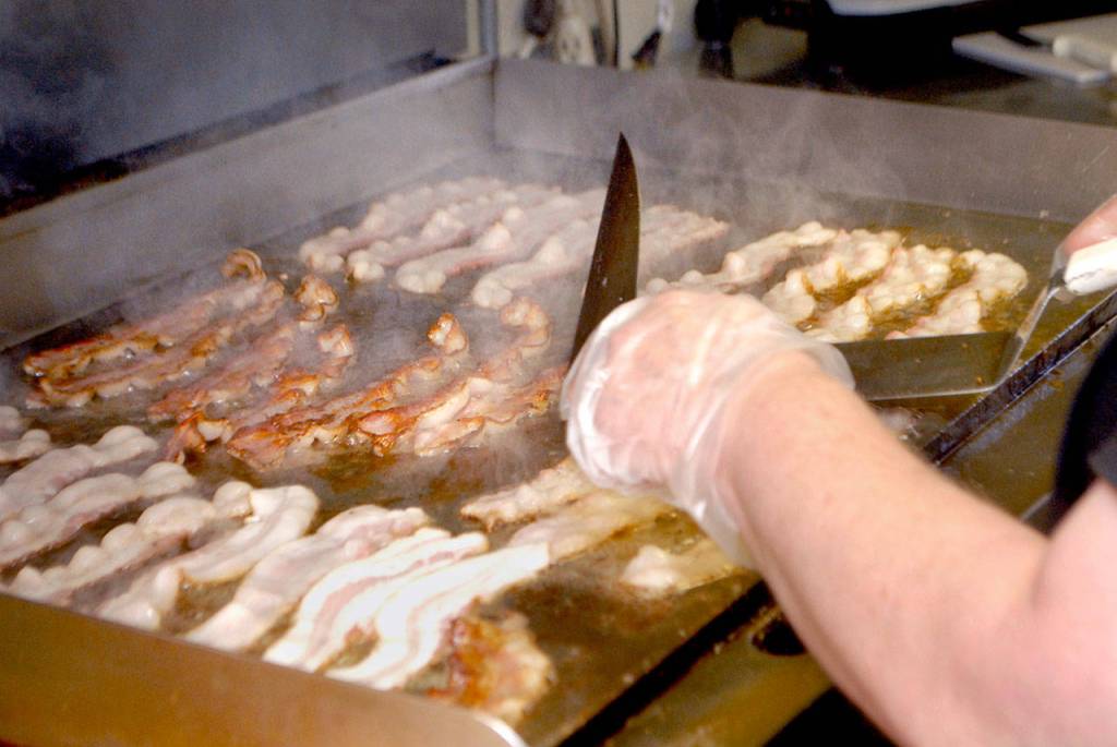 Bacon cooks on the grill Saturday morning in preparation for the lunchtime rush. (Keith Thorpe/Peninsula Daily News)