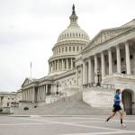 A man wearing a mask depicting American flags jogs past the U.S. Capitol Building on Tuesday, April 28, 2020, in Washington. The U.S. House of Representatives has canceled plans to return next week, a reversal after announcing it a day earlier. (Andrew Harnik/Associated Press)