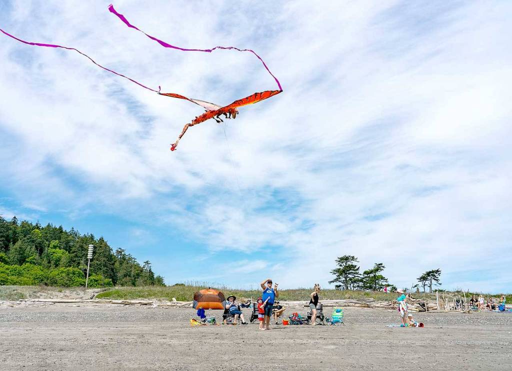 Tyler Poor and his son Rhys, 4, fly a kite at Fort Worden State Park on Saturday, May 9, 2020, while his family watches from behind. The family, from Puyallup, comes to the beach at Fort Worden for Mothers Day each year. (Steve Mullensky/for Peninsula Daily News)