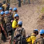 In this Aug. 27, 2015, file photo firefighters from the University of Alaska (Fairbanks) watch as a wildfire slowly creeps toward their fire break near Chelan, Wash. Newly released national plans for fighting wildfires during the coronavirus pandemic are hundreds of pages long but dont offer many details on how fire managers will get access to COVID-19 tests or exactly who will decide when a crew needs to enter quarantine. (Elaine Thompson/Associated Press file)