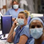 In this May 8 photo, registered nurse Katie Hammond looks up as she talks on the phone in the COVID-19 Intensive Care Unit at Harborview Medical Center, which is part of Seattle-area health care system UW Medicine, in Seattle. UW Medicine, which has played a leading role in responding to the coronavirus outbreak, is now facing a huge financial hole because of the fallout from COVID-19. (Elaine Thompson/Associated Press)