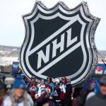 Fans pose below the NHL league logo at a display outside Falcon Stadium before an NHL Stadium Series outdoor hockey game between the Los Angeles Kings and Colorado Avalanche, at Air Force Academy, Colo., on Feb. 15, 2020. The NHL Players Associations executive board is voting on a 24-team playoff proposal as the return-to-play format. (David Zalubowski/Associated Press file)