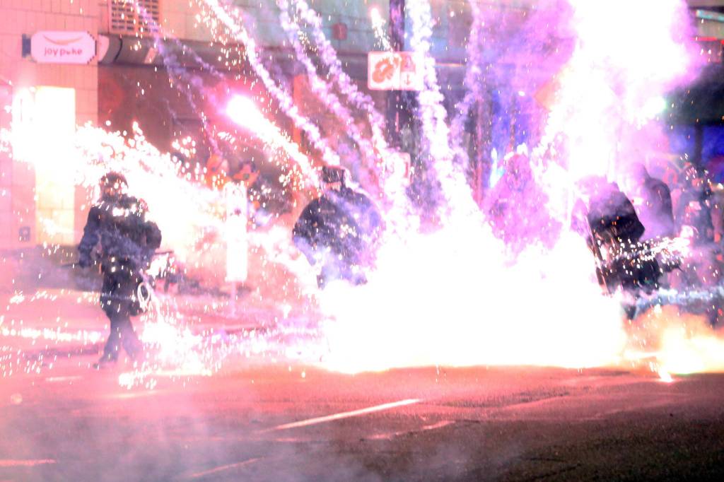 Police walk through fire and smoke as hundreds of people gathered to protest the Minneapolis police killing of George Floyd, Saturday, May 30, 2020, in Portland, Oregon. (Dave Killen/The Oregonian via AP)