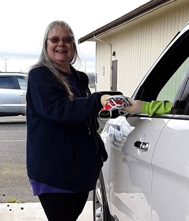 Sharon Clayton, president of the Sunbonnet Sue Quilt Club, accepts a donation of face masks to go to local health officials. Her first call for help from club members resulted in more than 200 face masks which grew into more than 4,500 as of last week. (Photo courtesy of Sunbonnet Sue Quilt Club)
