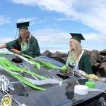 Port Angeles High School seniors Haley Pressley, left, and Bella Money decorate a car with streamers in the schools colors at the start of a graduation procession for the Class of 2020. (Keith Thorpe/Peninsula Daily News)