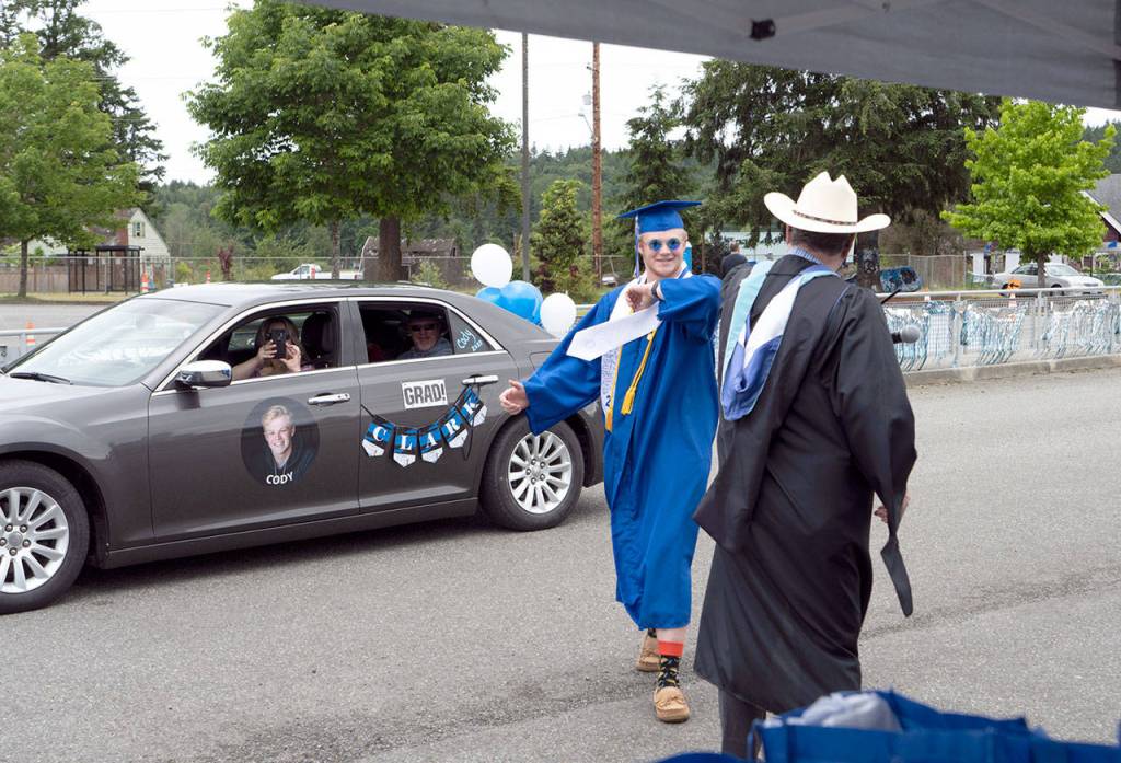 Cody Clark goes for an congratulatory elbow bump with Chimacum High School principal David Cartham during a drive-by graduation exercise on Saturday at the high school. (Steve Mullensky/for Peninsula Daily News)