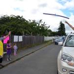 Grandma Keri Cook throws a pool noodle to daughter-in-law Wynn Hannam for granddaughter Noras birthday. The Hannam family, including Ellie, 5, and dad, Jared, waved to drivers as they honked in celebration of the Sequim 3-year-olds birthday. (Matthew Nash/Olympic Peninsula News Group)