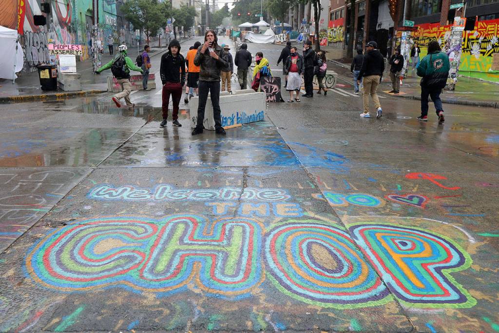 A sign on the street reads Welcome to the CHOP as protesters stand near barricades, Tuesday, June 30, 2020 at the CHOP (Capitol Hill Occupied Protest) zone in Seattle. Seattle Department of Transportation workers removed barricades about a block away Tuesday at the intersection of 10th Ave. and Pine St., but protesters quickly moved couches, trash cans and other materials in to replace the cleared barricades. The area has been occupied by protesters since Seattle Police pulled back from their East Precinct building following violent clashes with demonstrators earlier in the month. (AP Photo/Ted S. Warren)