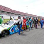 In this Monday June 22, 2020, file photo, NASCAR drivers Kyle Busch, left, and Corey LaJoie, right, join other drivers and crews as they push the car of Bubba Wallace to the front of the field prior to the start of the NASCAR Cup Series auto race at the Talladega Superspeedway in Talladega Ala. On Friday, June 26, 2020, The Associated Press reported on stories circulating online incorrectly asserting NASCAR allows a Black Lives Matter-themed car, but wont allow its audience to wear MAGA hats or other Trump clothing. The auto racing association has not banned Trump-themed clothing, according to NASCAR spokesman Mike Forde. (John Bazemore/Associated Press)