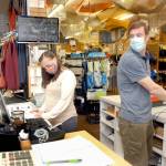Browns Outdoor co-owner Eric Brown, right, looks back a a second cash register as bookkeeper and buyer Dayna Brown examines a cataloge in the downtown Port Angeles sporting goods store. (Keith Thorpe/Peninsula Daily News)