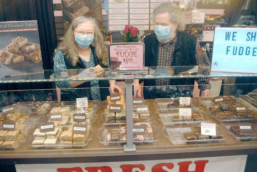 Northwest Fudge and Confections co-owners Lindi and Bob Lumens wear their masks behind the fudge counter in their downtown Port Angeles candy store. (Keith Thorpe/Peninsula Daily News)