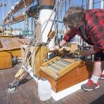 Sound Experience intern Jon Holt, 18, removes old varnish Thursday afternoon from the deck of the Schooner Adventuress. Holt has spent the summer working aboard the docked ship before starting his senior year at Port Townsend High School. (Nicholas Johnson/Peninsula Daily News)