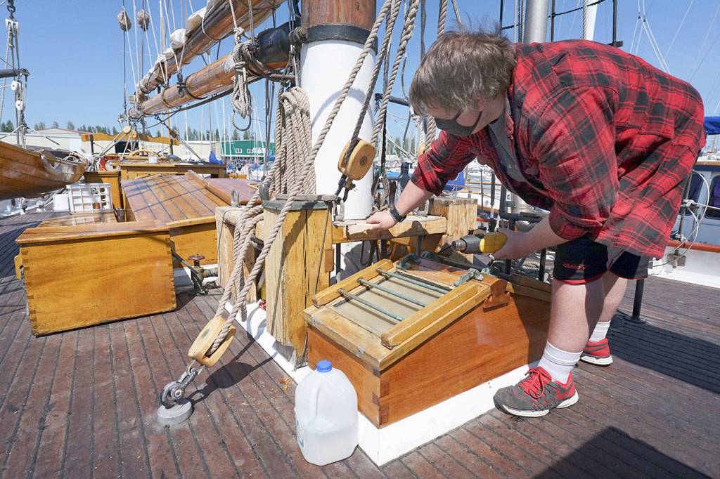 Sound Experience intern Jon Holt, 18, removes old varnish Thursday afternoon from the deck of the Schooner Adventuress. Holt has spent the summer working aboard the docked ship before starting his senior year at Port Townsend High School. (Nicholas Johnson/Peninsula Daily News)