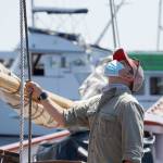 Capt. Nate Seward tugs on a line Thursday afternoon while looking up at Starlings gathered atop a mast on the Schooner Adventuress. (Nicholas Johnson/Peninsula Daily News)