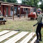 Head of School Emily Gohn stains fence planks for a new outdoor preschool area.