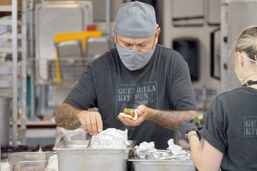 Walter Zamora tops off his pork belly bao with shredded carrots, sliced pickles and cilantro Friday at Lilas Kitchen in Port Townsend. Friday was the debut of his new culinary venture: The Guerrilla Kitchen. (Nicholas Johnson/Peninsula Daily News)