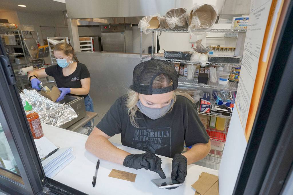 Ashley Avery of The Guerrilla Kitchen takes orders Friday at a walk-up window at Lilas Kitchen in Port Townsend. On Fridays, The Guerrilla Kitchen shares the new commercial kitchen space with Mo-Chilli BBQ, each serving customers through separate walk-up windows. (Nicholas Johnson/Peninsula Daily News)
