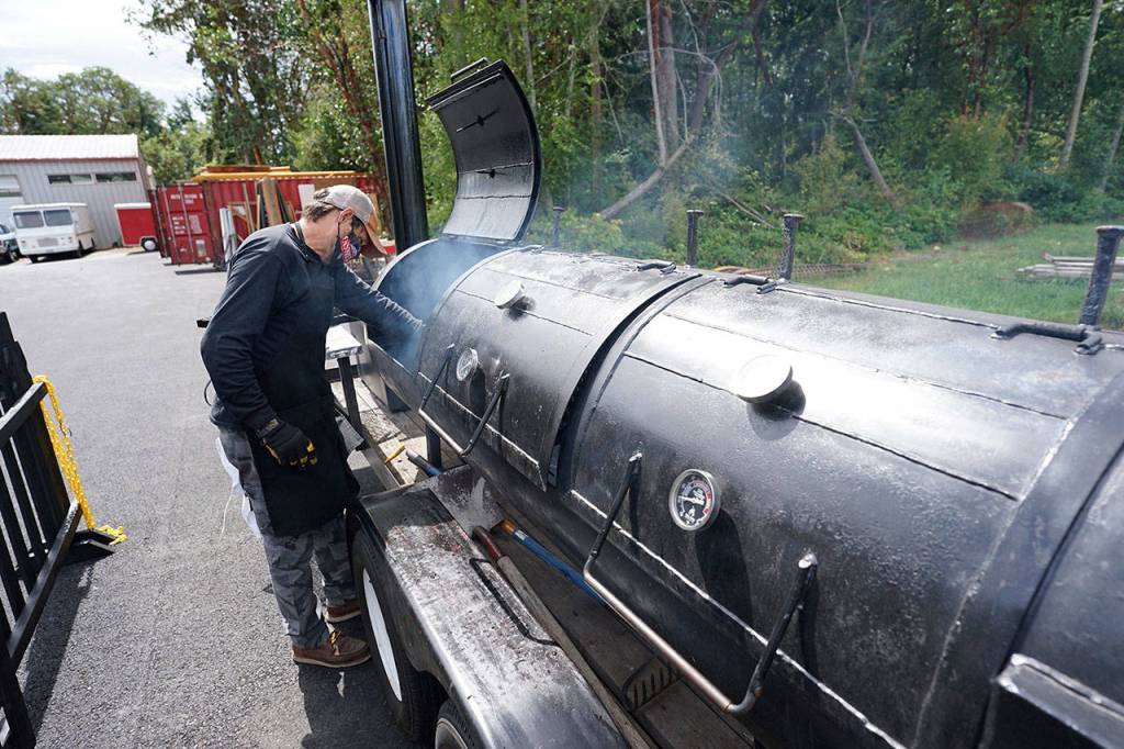 Mike Harbin of Mo-Chilli BBQ cleans his 325-gallon smoker after a long day of barbecuing meats Thursday outside Lilas Kitchen in Port Townsend. Harbin recently relocated the smoker, which he purchased last summer ahead of THING festival, from a friends field to the Lilas Kitchen property where he and his team serve food through a walk-up window on Thursdays and Fridays. (Nicholas Johnson/Peninsula Daily News)