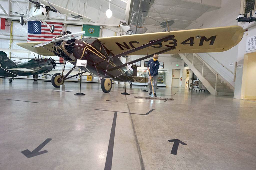 Gavin Miner, 14, of Bellingham sweeps inside the Port Townsend Aero Museum on Saturday morning, the museums first day open since it closed in March. Tape arrows on the ground direct visitors through the museum space. Miner participates in the museums youth program, which reopened June 17, and also volunteers at the reopened museum. (Nicholas Johnson/Peninsula Daily News)
