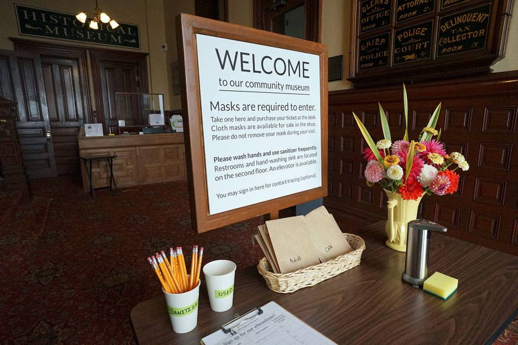 A sign, flowers, hand sanitizer and bagged face masks greet visitors to the Jefferson Museum of Art & History on Saturday, the museums first day open since it closed in March due to the growing coronavirus pandemic. (Nicholas Johnson/Peninsula Daily News)