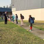 Students stand in a well-spaced line Tuesday morning as they wait to have their temperatures checked on the first day of in-person classes at Chimacum Elementary School in Chimacum. (Jason Lynch)