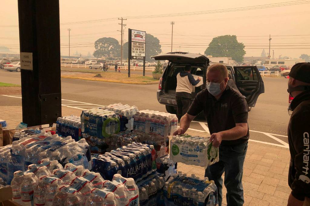 Jonathan Thompson of the Keizer, Oregon, Chamber of Commerce delivers donated bottled water Tuesday, Sept. 8, 2020, to the Oregon State Fairgrounds in Salem, which is now an evacuation center as wildfires threaten towns in Oregon. High winds kicked up wildfires across the Pacific Northwest on Tuesday, burning hundreds of thousands of acres, mostly destroying the small town of Malden in eastern Washington state and forcing evacuations and highway closures in Oregon. (Andrew Selsky/Associated Press)