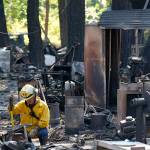 A firefighter working to put out hotspots pauses in the rubble of a structure destroyed by fire Tuesday, Sept. 8, 2020, after an overnight wildfire in Graham, Wash., overnight south of Seattle. (Ted S. Warren/Associated Press)